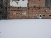 an old building with graffiti on the wall next to snow in wintertime near city street