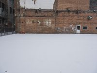 an old building with graffiti on the wall next to snow in wintertime near city street