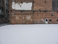 an old building with graffiti on the wall next to snow in wintertime near city street