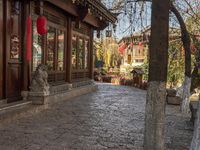 an old building with stone benches next to it and the red lanterns hanging over it