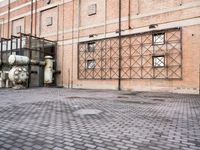 several large steel pipes standing in front of an old building with brick walls and a gate