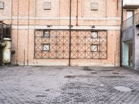 several large steel pipes standing in front of an old building with brick walls and a gate