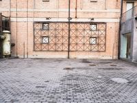several large steel pipes standing in front of an old building with brick walls and a gate