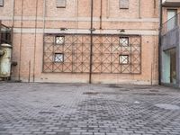 several large steel pipes standing in front of an old building with brick walls and a gate