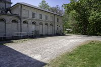 an old building is surrounded by lots of grass and trees and some shrubs in the front of it