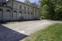 an old building is surrounded by lots of grass and trees and some shrubs in the front of it