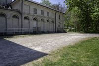 an old building is surrounded by lots of grass and trees and some shrubs in the front of it