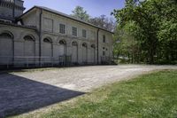 an old building is surrounded by lots of grass and trees and some shrubs in the front of it