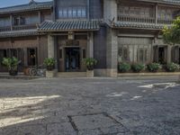 an old chinese building and some flowers outside it, with a man riding a horse