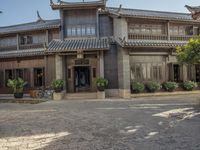 an old chinese building and some flowers outside it, with a man riding a horse