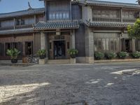 an old chinese building and some flowers outside it, with a man riding a horse