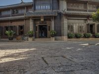 an old chinese building and some flowers outside it, with a man riding a horse