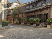 a old chinese street is full of potted plants and bikes on the cobblestones