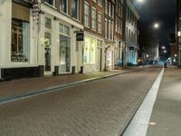 a person walking down the side walk of an old fashioned city street at night in the uk