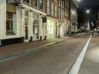 a person walking down the side walk of an old fashioned city street at night in the uk