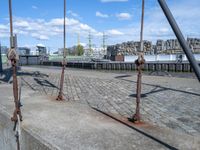 some old fashioned metal pole on the road near water and a city and waterfront area