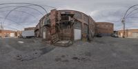 a fish - eye view shows many circular buildings in an old area with a red brick building