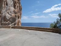 this is an old parking lot near a cliff with the ocean in the background and blue sky above