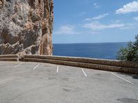 this is an old parking lot near a cliff with the ocean in the background and blue sky above