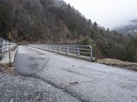 an old railroad bridge is partially over and over the road in the mountains on a cloudy day