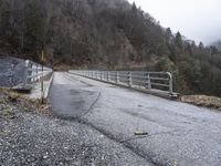 an old railroad bridge is partially over and over the road in the mountains on a cloudy day