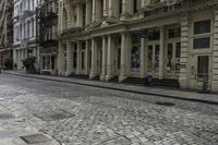 an old stone road with a bicycle parked on the sidewalk and an older building in the background