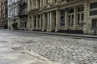 an old stone road with a bicycle parked on the sidewalk and an older building in the background