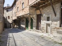 old street with stone floors and a green door and windows in an italian village back alley