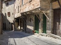 old street with stone floors and a green door and windows in an italian village back alley