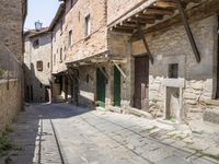 old street with stone floors and a green door and windows in an italian village back alley