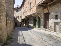 old street with stone floors and a green door and windows in an italian village back alley