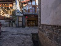 an empty alley of small buildings and old stone streets in china with people walking down them