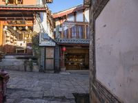 an empty alley of small buildings and old stone streets in china with people walking down them