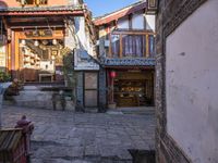 an empty alley of small buildings and old stone streets in china with people walking down them