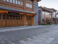 there is a cobble stone sidewalk with a clock in between buildings and an umbrella pole on the side of it