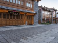 there is a cobble stone sidewalk with a clock in between buildings and an umbrella pole on the side of it