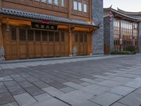 there is a cobble stone sidewalk with a clock in between buildings and an umbrella pole on the side of it