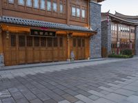 there is a cobble stone sidewalk with a clock in between buildings and an umbrella pole on the side of it