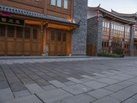 there is a cobble stone sidewalk with a clock in between buildings and an umbrella pole on the side of it