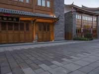 there is a cobble stone sidewalk with a clock in between buildings and an umbrella pole on the side of it