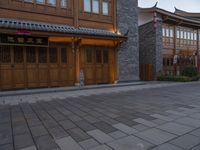 there is a cobble stone sidewalk with a clock in between buildings and an umbrella pole on the side of it