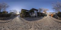 360 - view of a road surrounded by trees and houses in the back ground of the street