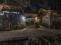 an outdoor area with some plants and lights in the night sky, and several lanterns that are hanging