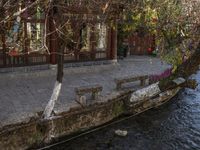 there is a boat parked on the side of a stream outside of a building with a fence in front