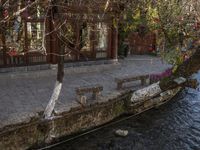 there is a boat parked on the side of a stream outside of a building with a fence in front