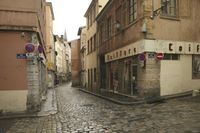 an empty street with several tall buildings in the background in the city with cobblestones