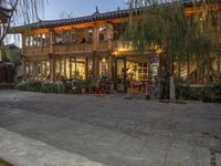 people are walking around outside an old building with shops and stores behind them at dusk