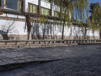 a bricked - in walkway with a stone planter and cement steps that lead down to a building