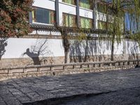 a bricked - in walkway with a stone planter and cement steps that lead down to a building