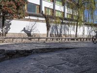 a bricked - in walkway with a stone planter and cement steps that lead down to a building